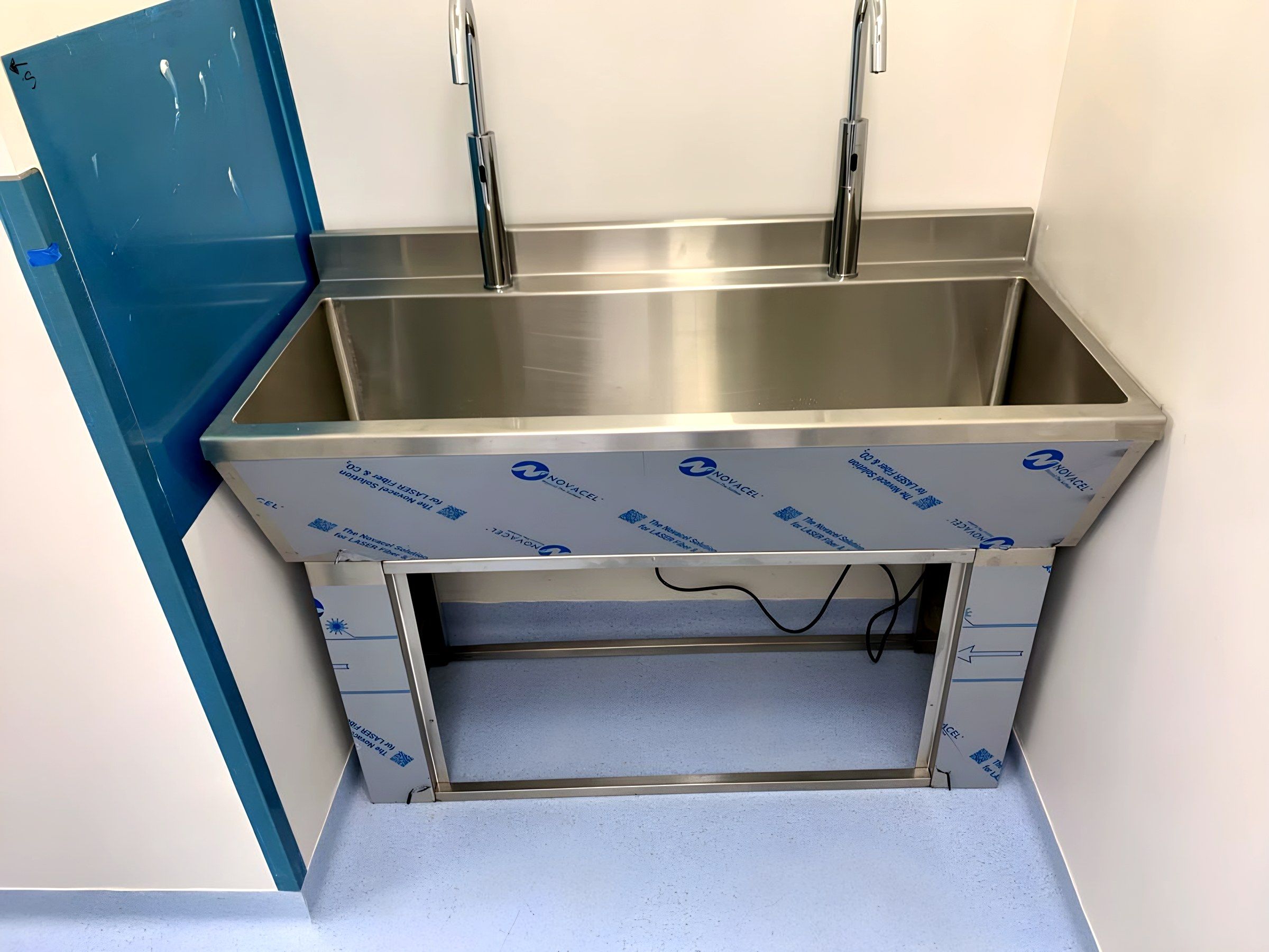 Tarja de lavado corrida con dos estaciones y grifería de cuello alto, instalada en su nicho.
