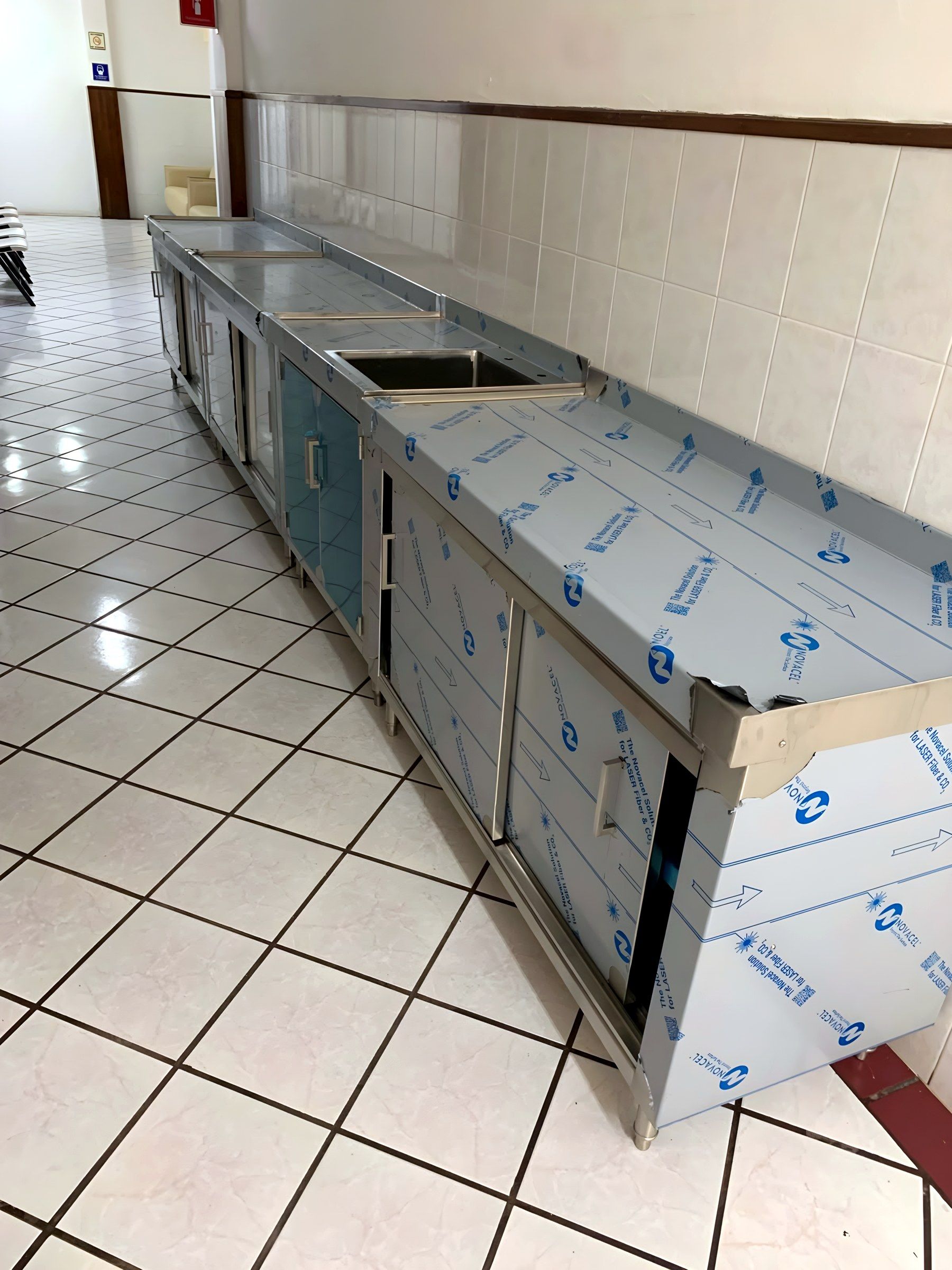 Mueble corrido de acero inoxidable con tarjas y gabinetes, recién instalado.