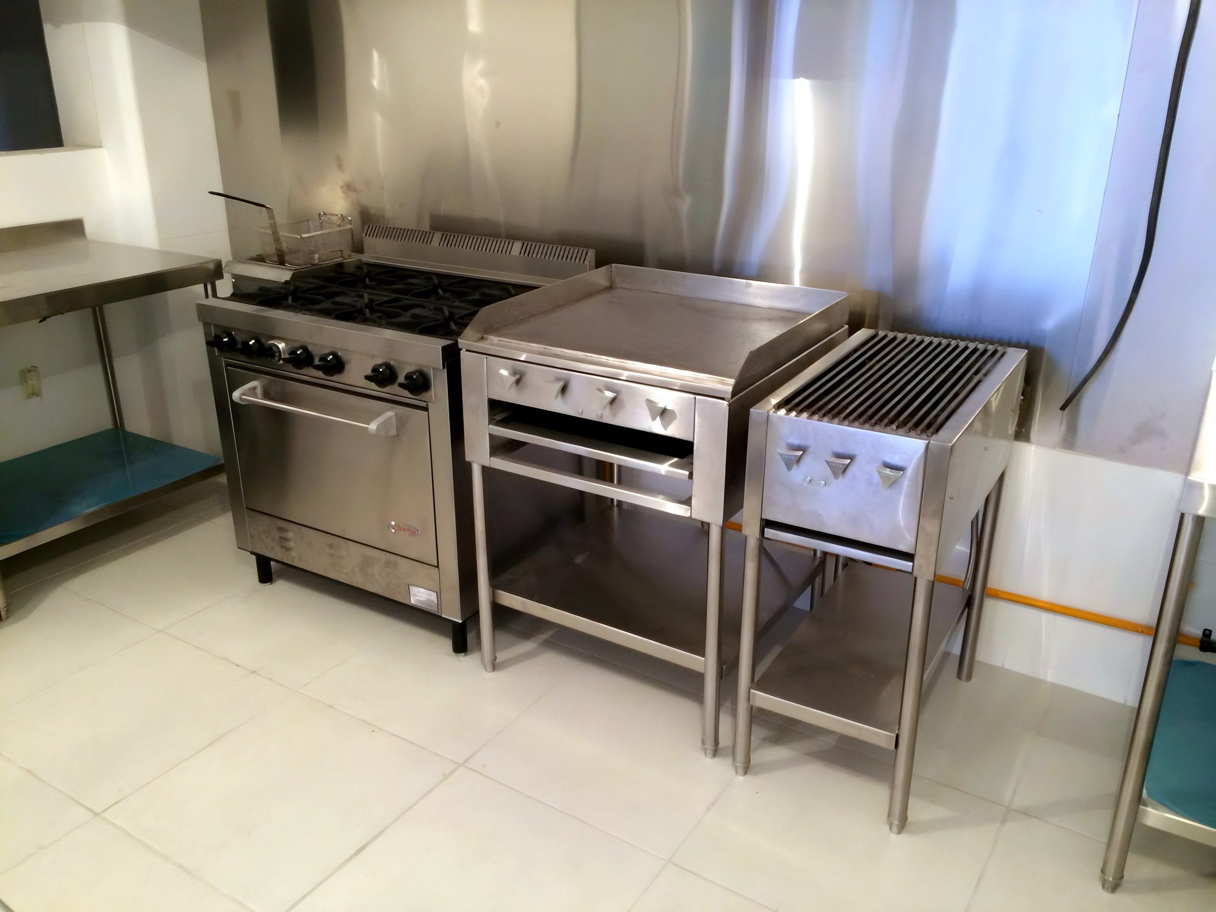 Estufa con horno, plancha y asador alineados junto a una mesa de trabajo.