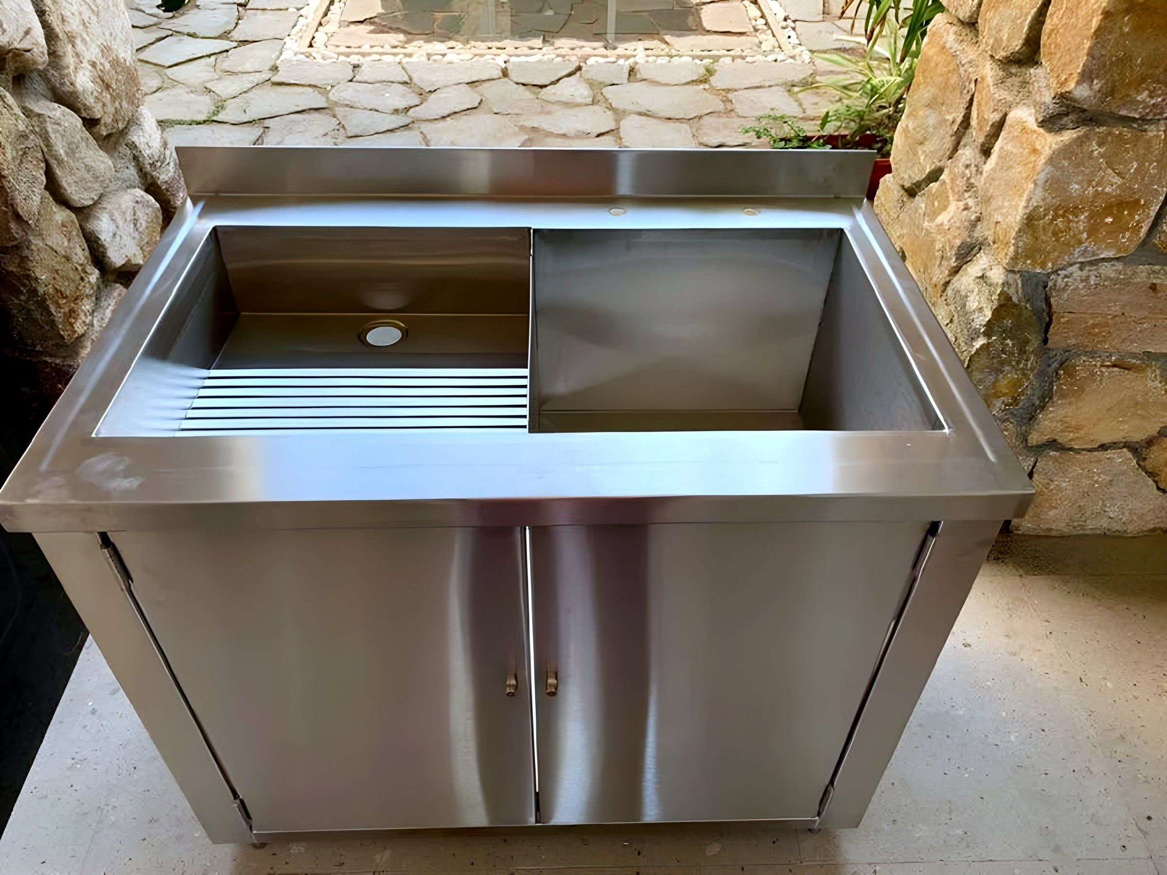 Mueble con tarja, escurridor ranurado y puertas abatibles en acero inoxidable.